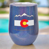 Stemless wine glass with a lid and Colorado logo design. Pictured on a table by the pool.