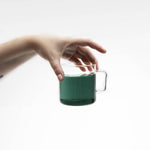 Hand holding a green mug of brewed Blue Lullaby butterfly pea tea