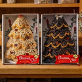 Two boxed bird seed Christmas trees, one light and one dark seed, on a wood shelf