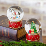 Horse snow globe on a red drum base, shown with the matching Christmas tree snow globe