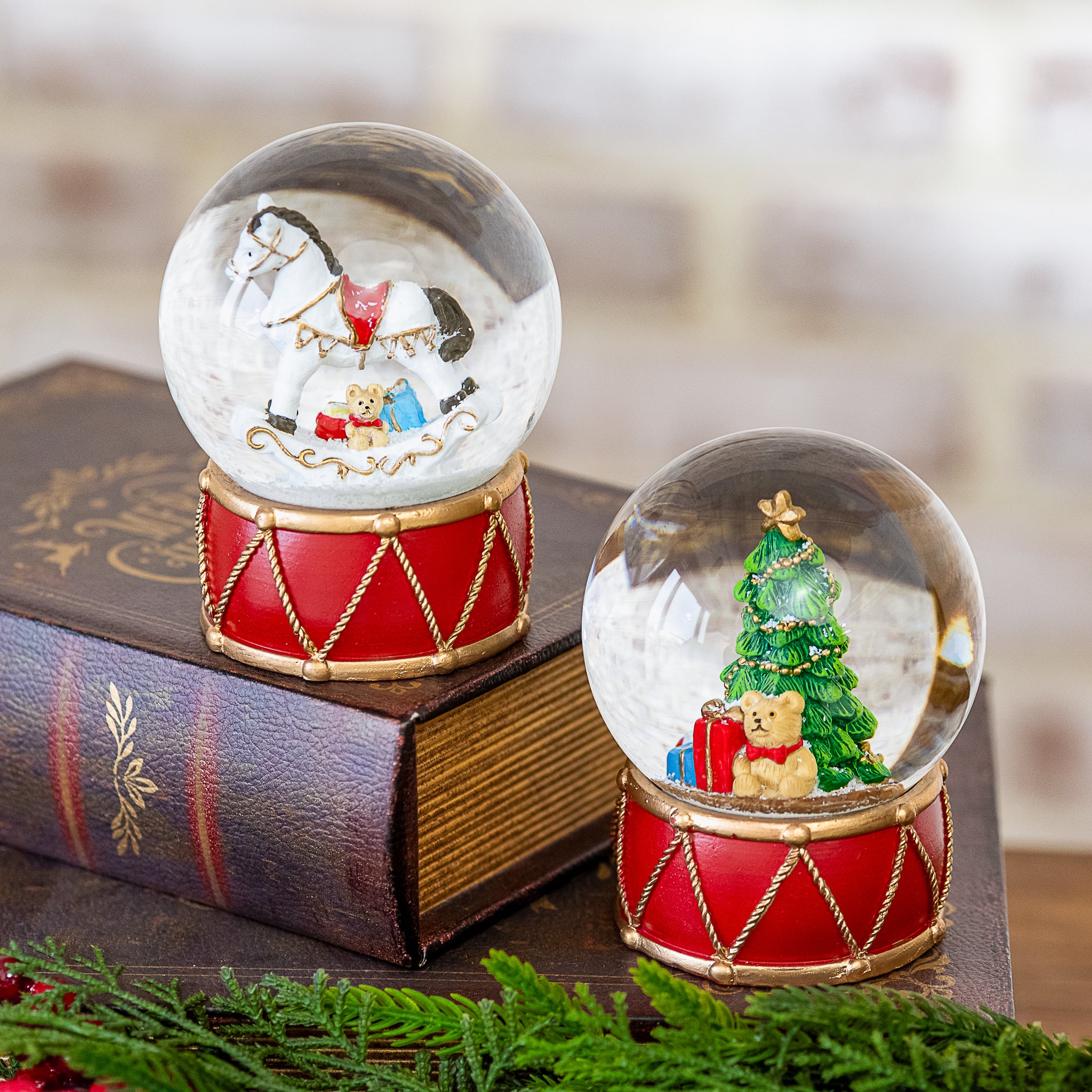 Horse snow globe on a red drum base, shown with the matching Christmas tree snow globe