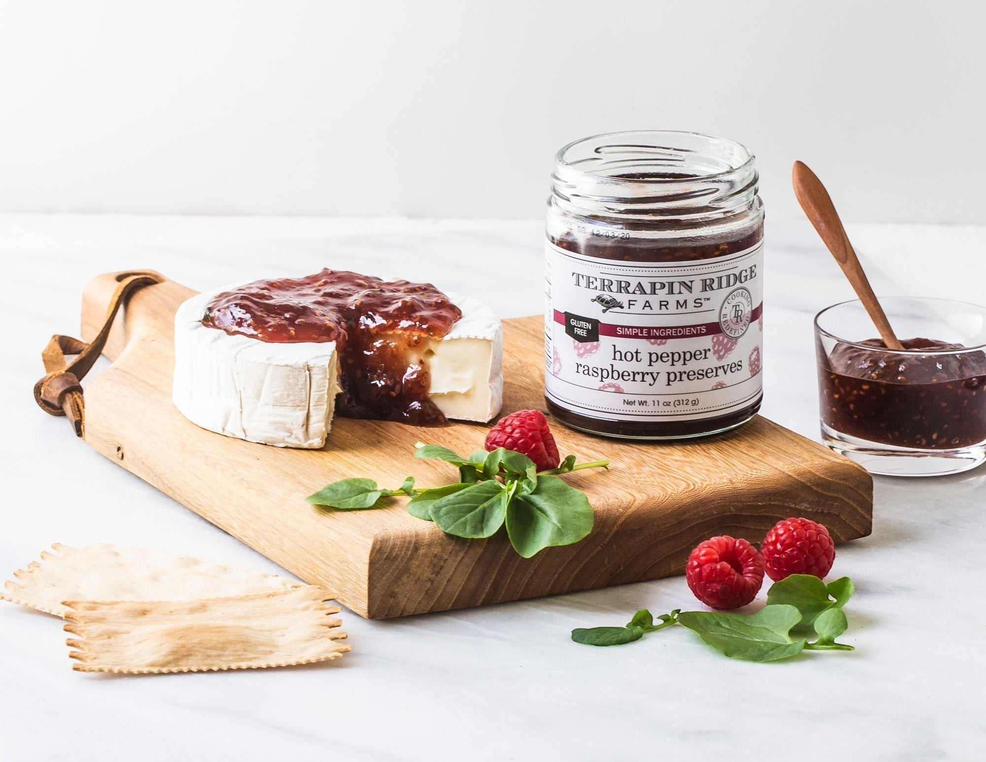 Brie topped with Hot Pepper Raspberry Preserves with crackers and fresh raspberries