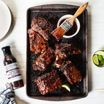 Ribs glazed with Raspberry Peach Chipotle Sauce with a basting brush and lime wedges