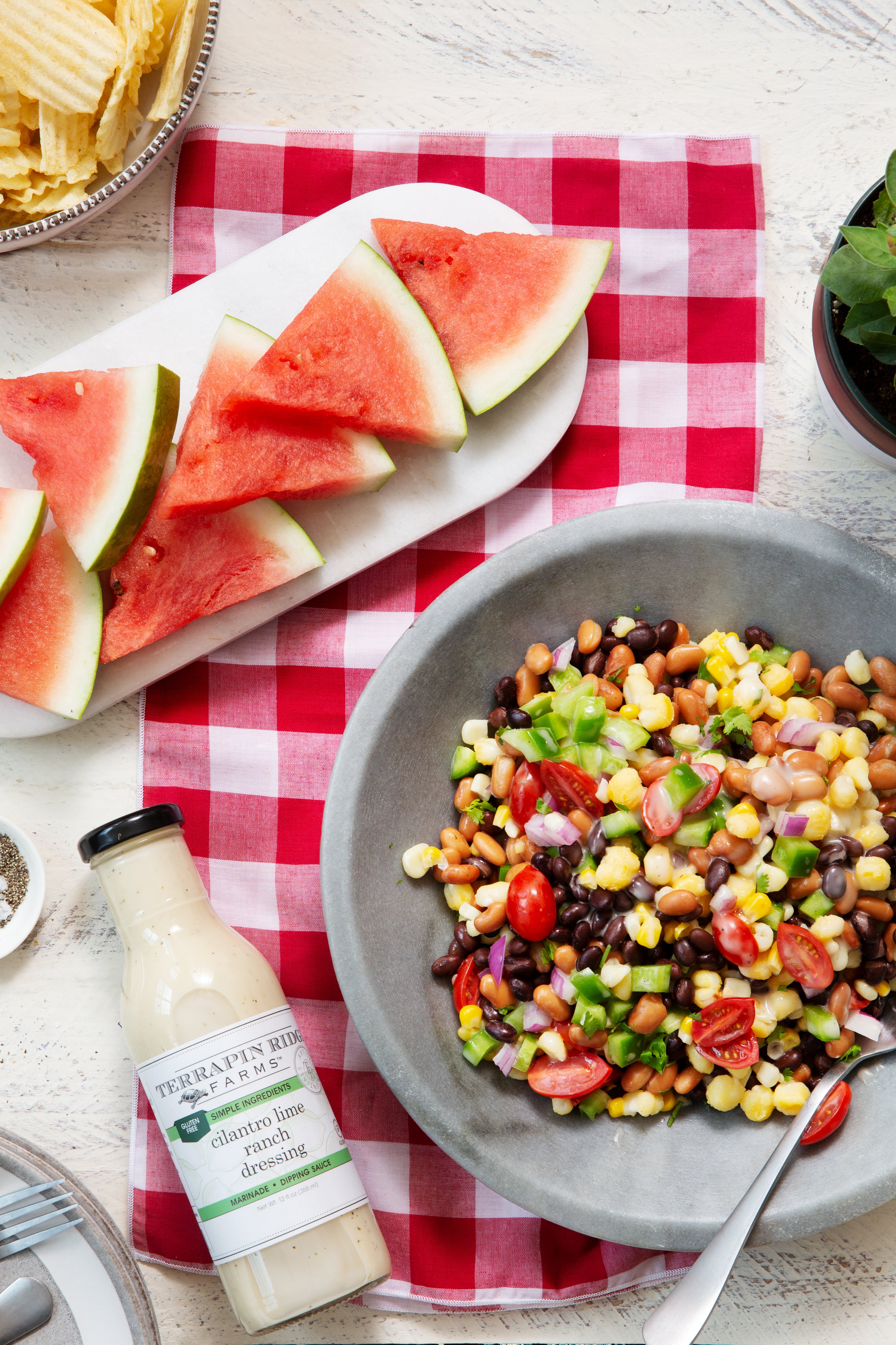 Bean and corn salad with watermelon and chips alongside Cilantro Lime Ranch Dressing