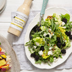 Green salad with blackberries, avocado and feta beside Lemon Honey Vinaigrette