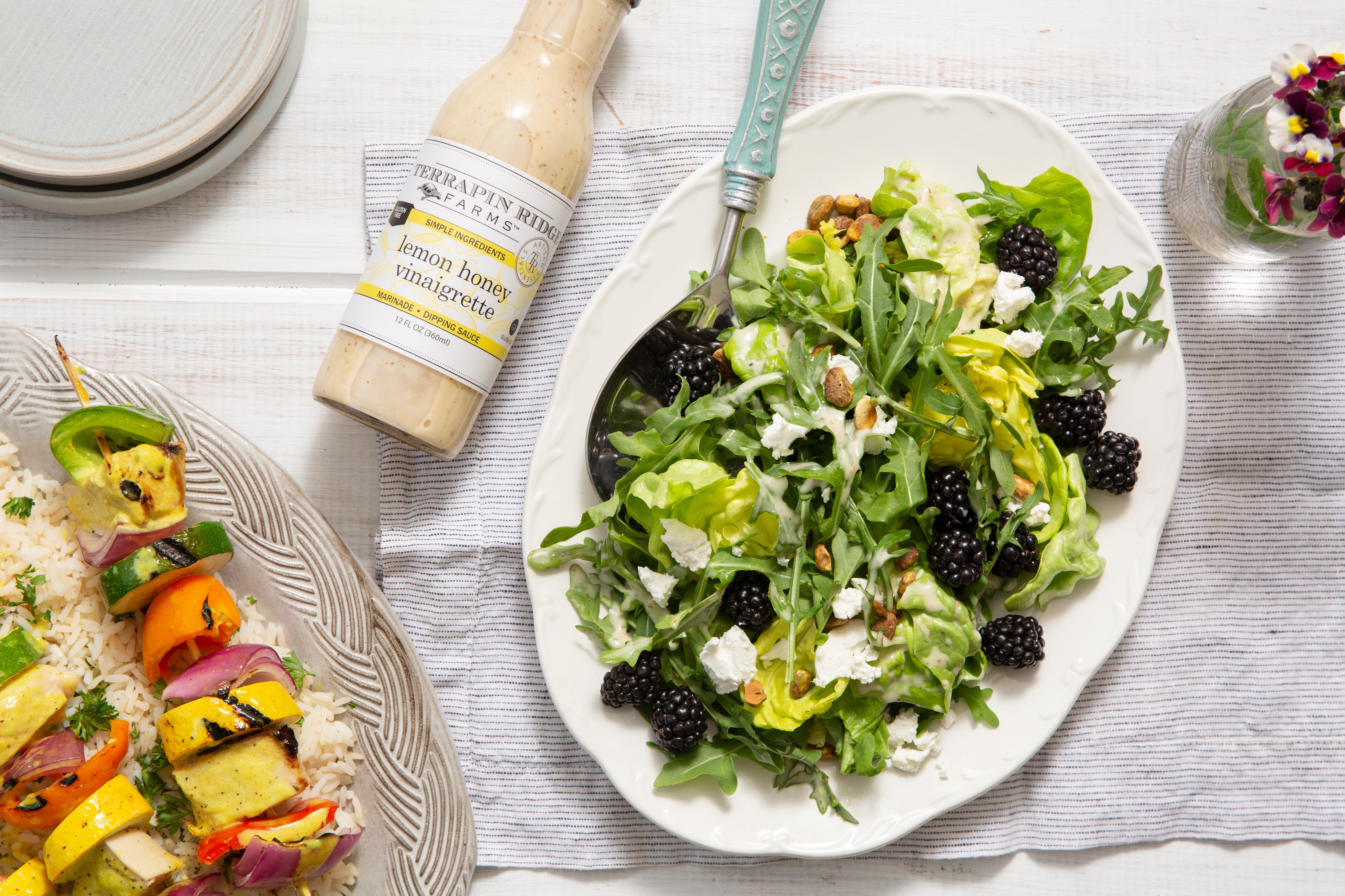 Green salad with blackberries, avocado and feta beside Lemon Honey Vinaigrette