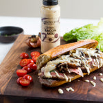 Steak sandwich topped with Bacon Aioli on a wooden board