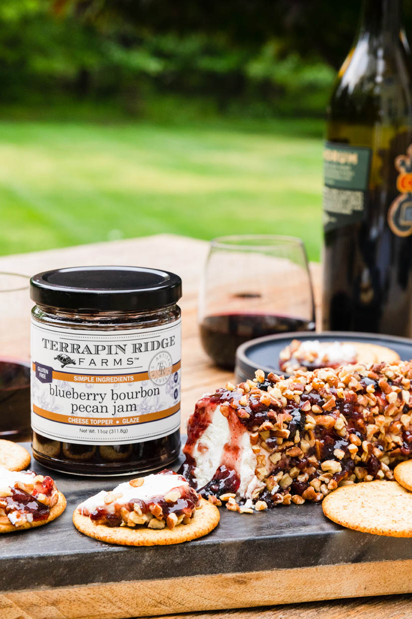 Goat cheese topped with Blueberry Bourbon Pecan Jam and pecans, served with crackers