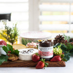 Brie topped with Strawberry & Fig Jam on a holiday cheese board with fresh strawberries
