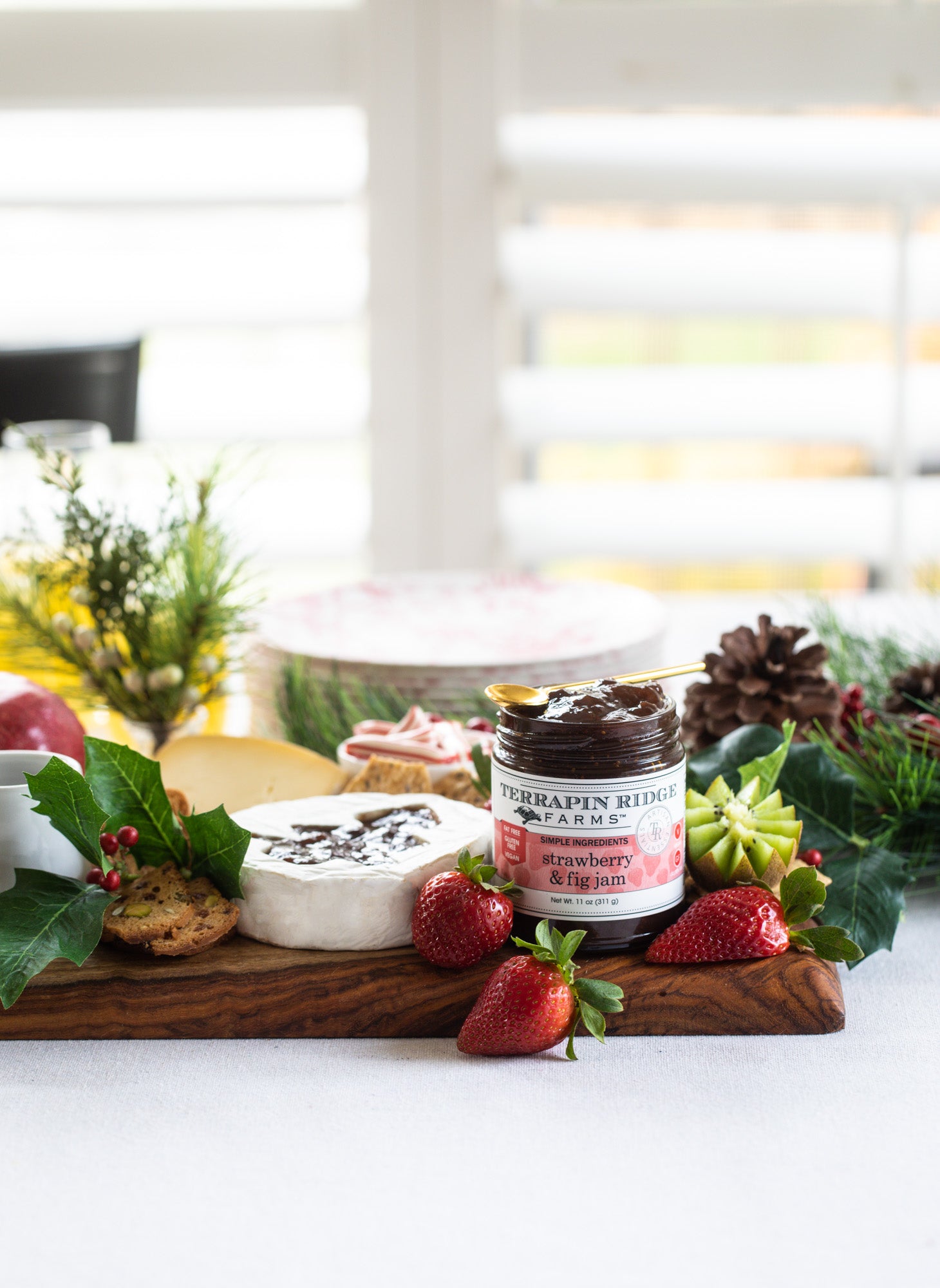 Brie topped with Strawberry & Fig Jam on a holiday cheese board with fresh strawberries