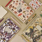 Spiral-bound art journal with a painted iris cover, interior pages
