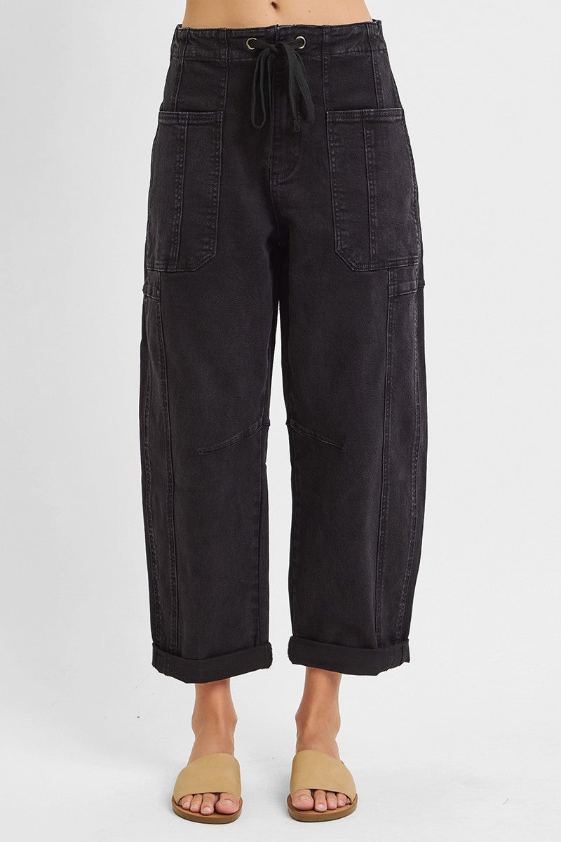 Black barrel leg cargo jeans showing curved thigh and tapered cropped hem