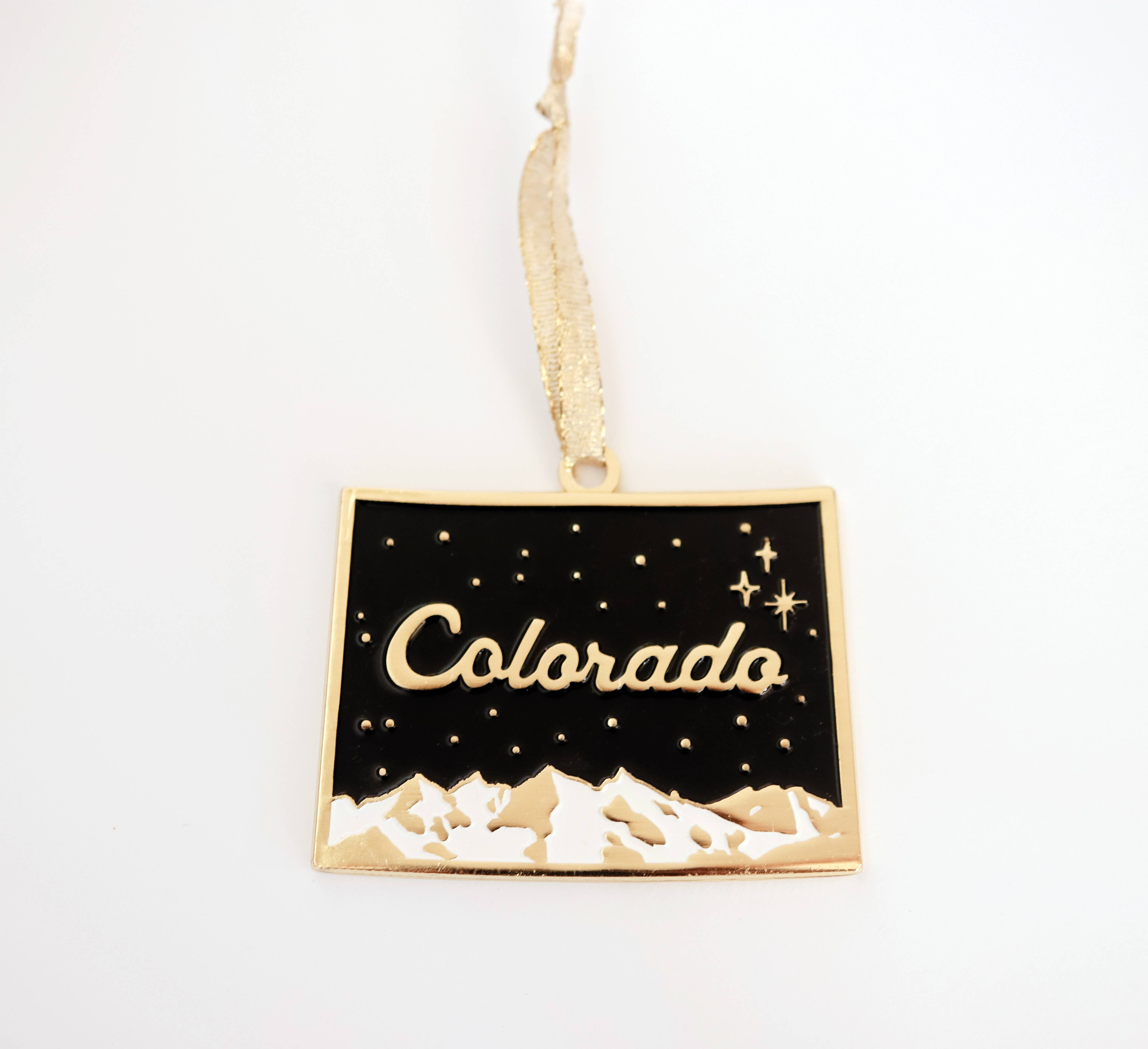 Black and gold enamel Colorado state ornament with a starry night sky and snowy peaks, on a gold ribbon
