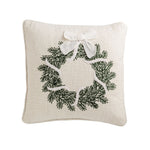 Square cream pillow with a green crewel-embroidered evergreen wreath and white bow