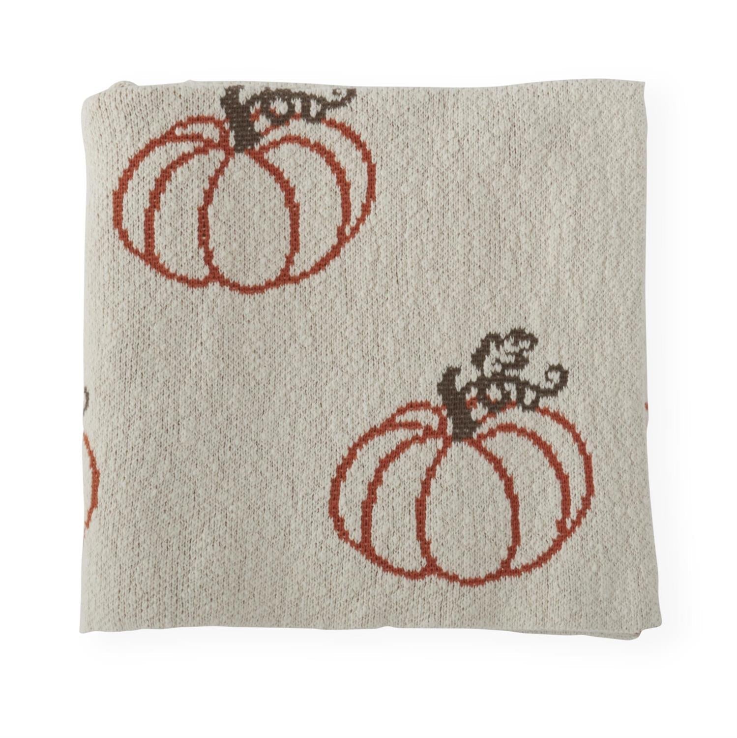 Cream knit throw blanket folded, showing rust orange pumpkin motif