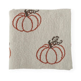 Cream knit throw blanket folded, showing rust orange pumpkin motif