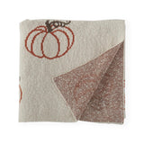 Folded cream knit pumpkin throw with corner turned back to show the rust and cream reverse