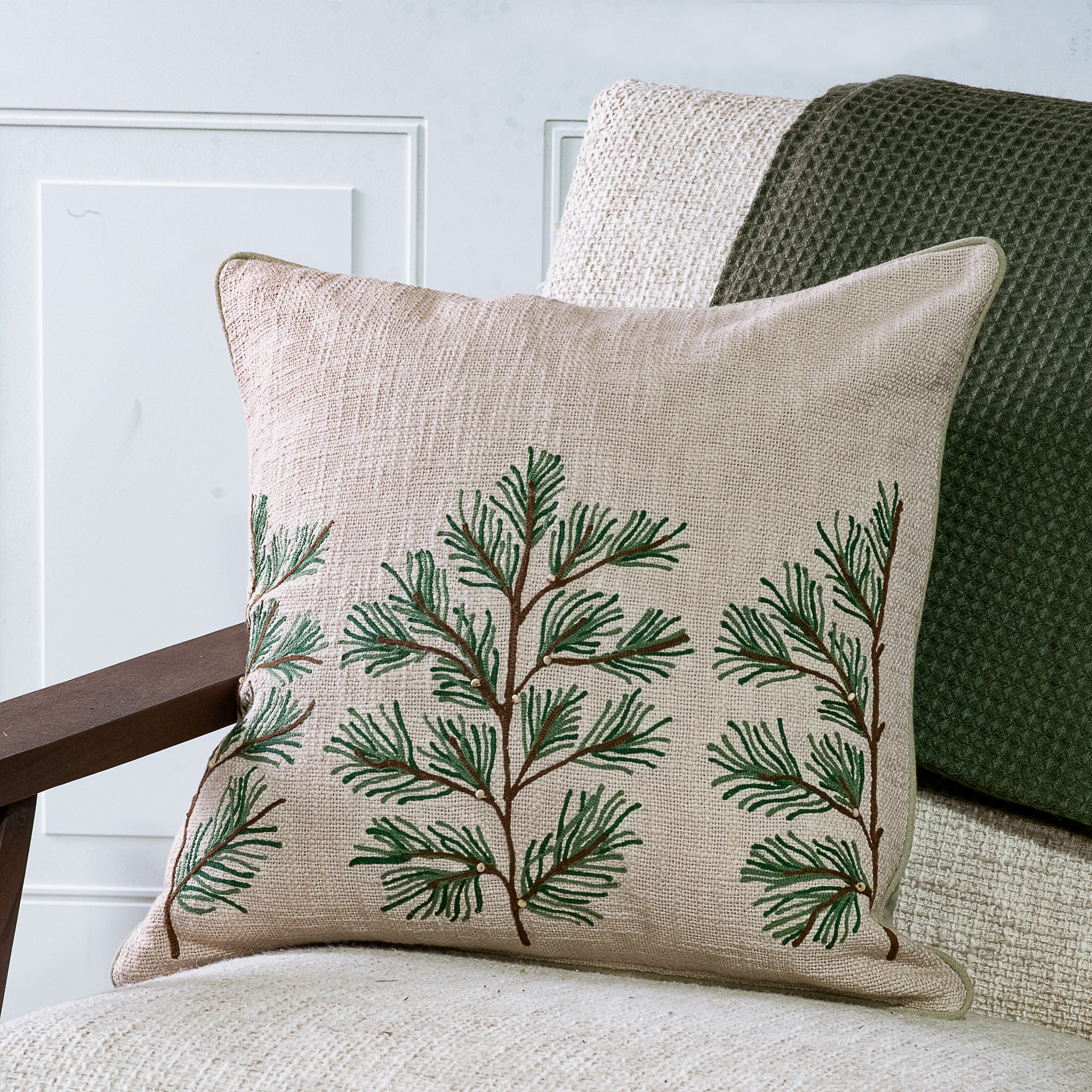 Oatmeal pillow embroidered with green pine sprigs
