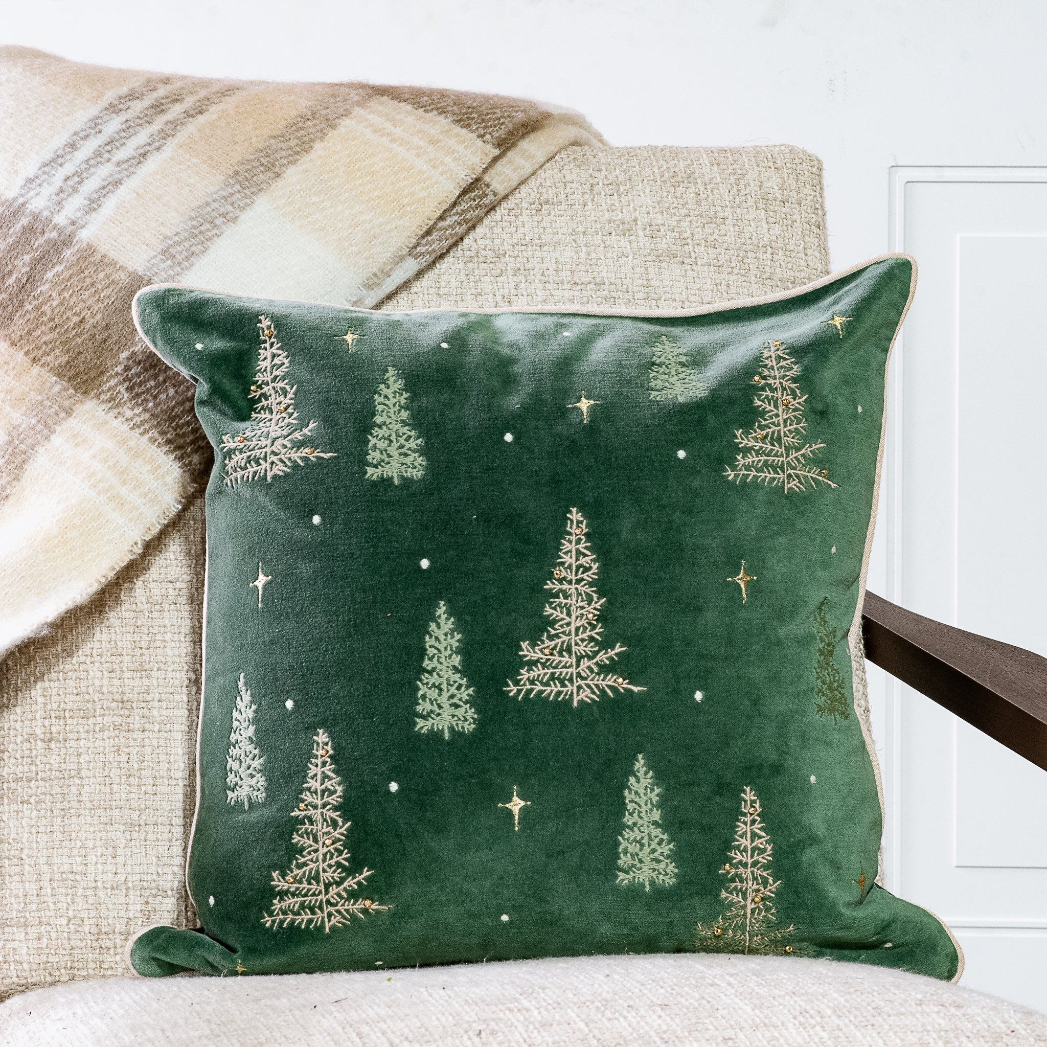Deep green pillow embroidered with small evergreen trees and stars