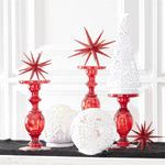 White acrylic LED globes lit on a mantel beside red glass candlesticks and red glittered stars