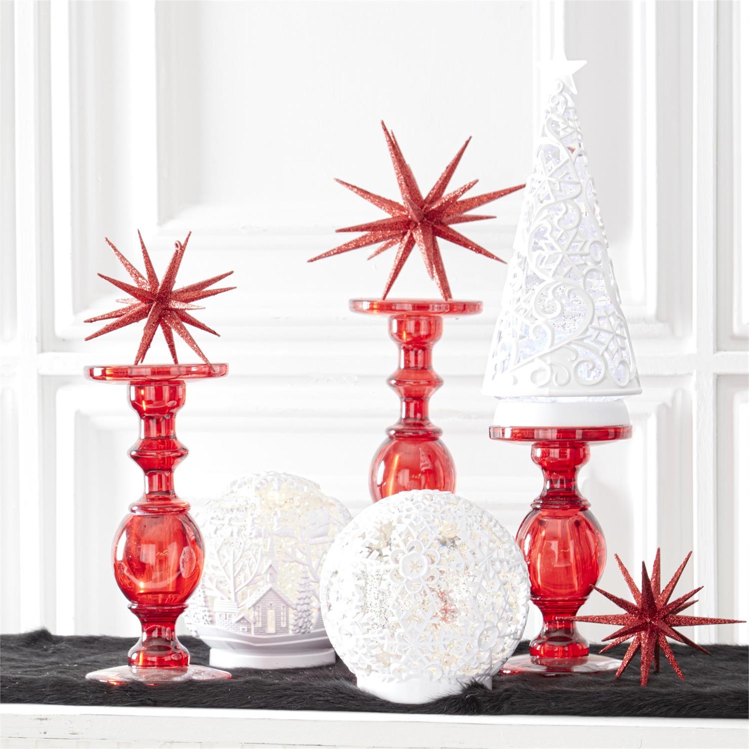 White acrylic LED globes lit on a mantel beside red glass candlesticks and red glittered stars
