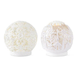 Two white acrylic globes, one with snowflake cutouts and one with a cutout winter village scene