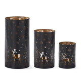 Three black metal cylinder lanterns with deer, tree and snowflake cutouts and copper-toned interiors