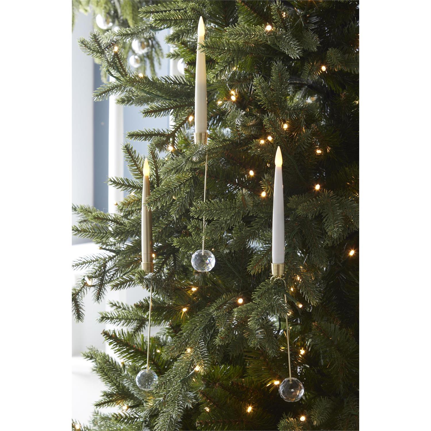 Gold LED taper candles clipped onto the branches of a lit Christmas tree with crystal weights