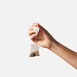 Compostable Minty Blue tea bag held between two fingers