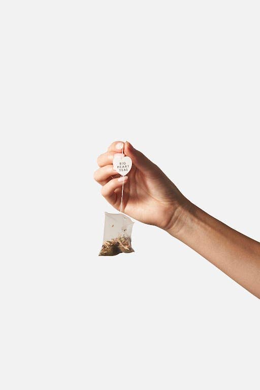 Compostable Minty Blue tea bag held between two fingers