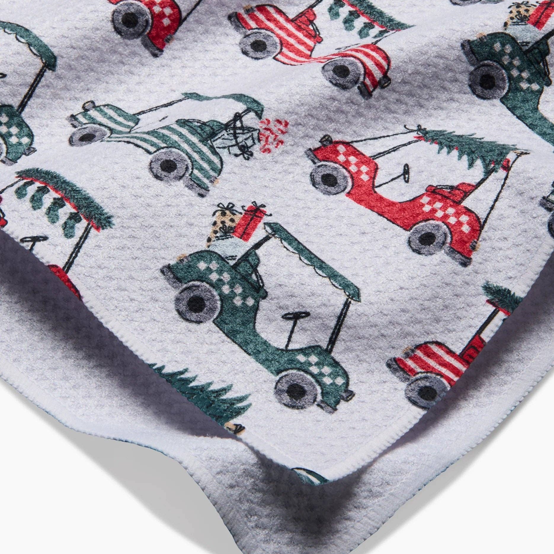 Close-up of red and green golf cart Christmas tree print on tea towel