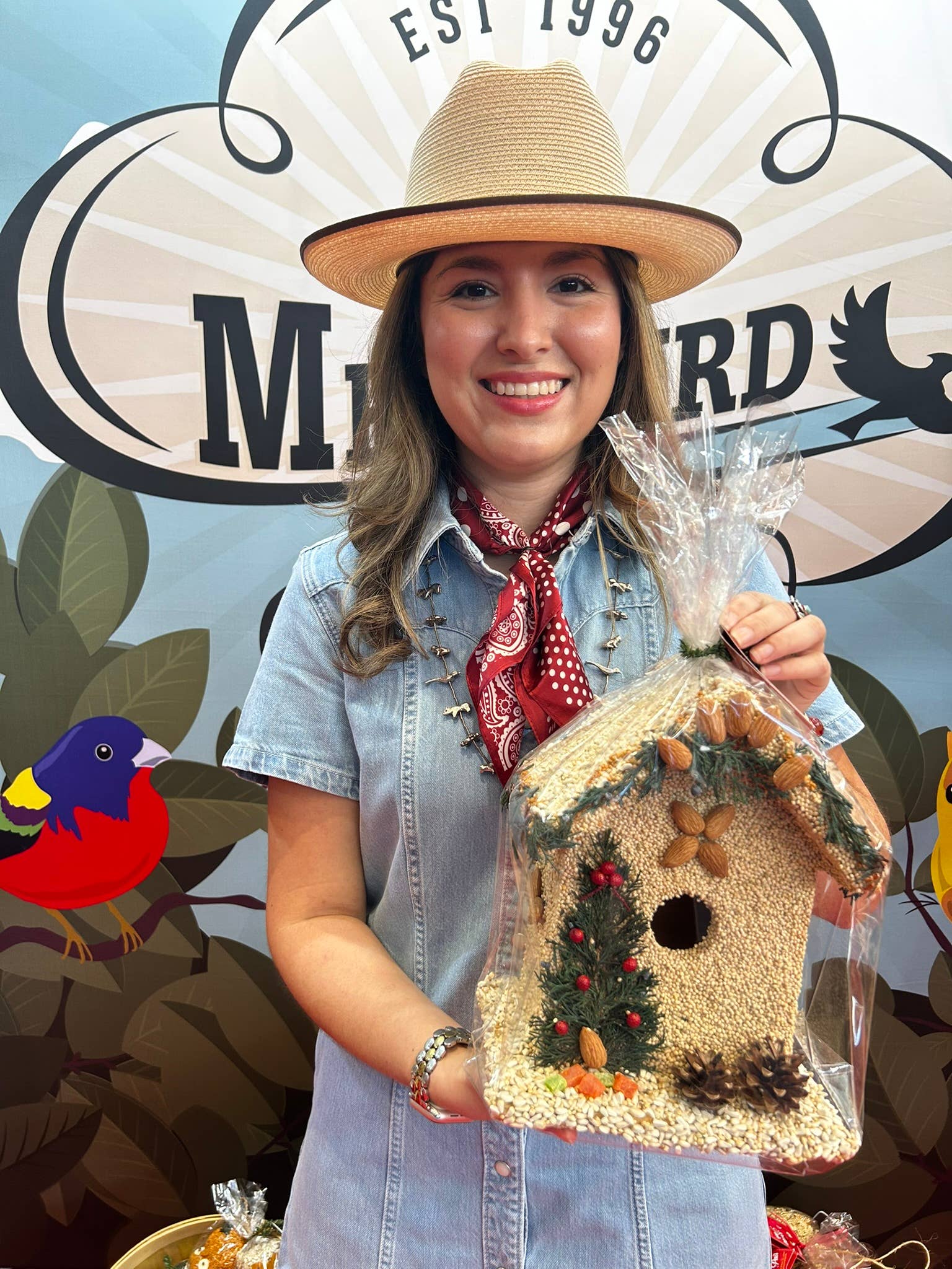 Woman in a straw hat holding a juniper seed-covered birdhouse