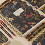 Spiral-bound art journal with a Forest Flowers illustrated cover, interior pages