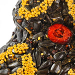 Close-up of black sunflower seeds, gold millet, and a dried cranberry on the seed tree
