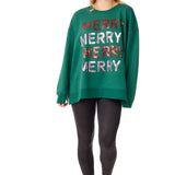 Model in an oversized green sweatshirt with stacked MERRY lettering in red and sequins