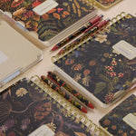 Spiral-bound art journal with a Forest Flowers illustrated cover, interior pages