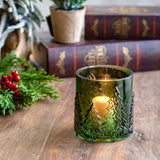 Small green embossed glass votive holder with a lit candle