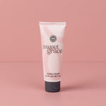 Sweet Grace Hand Cream tube with flip-top cap standing on a pink surface