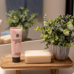 Sweet Grace Hand Cream styled on a wooden tray on a bathroom counter with soap and a small plant