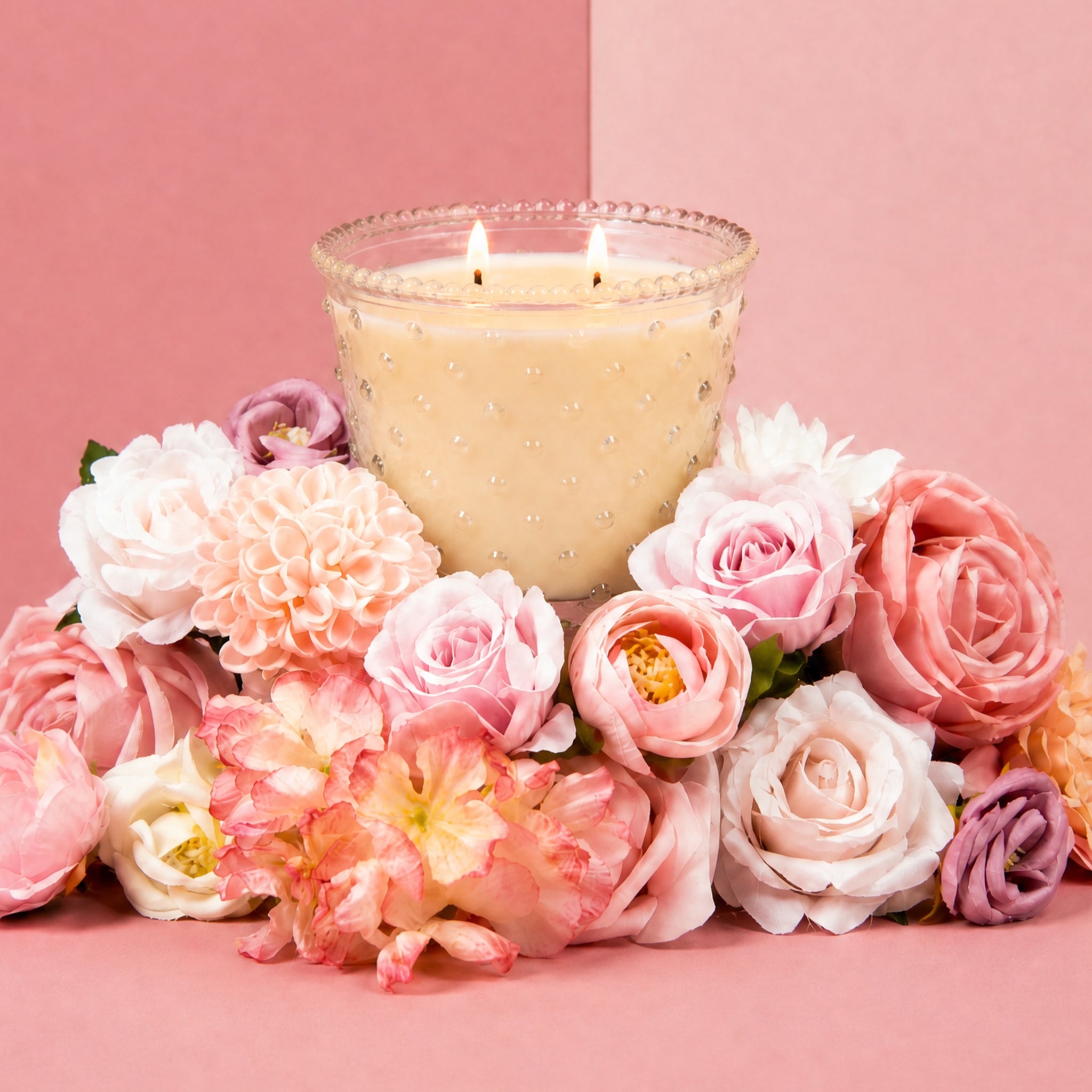 Bridgewater Sweet Grace hobnail candle glowing beside pink and white flowers