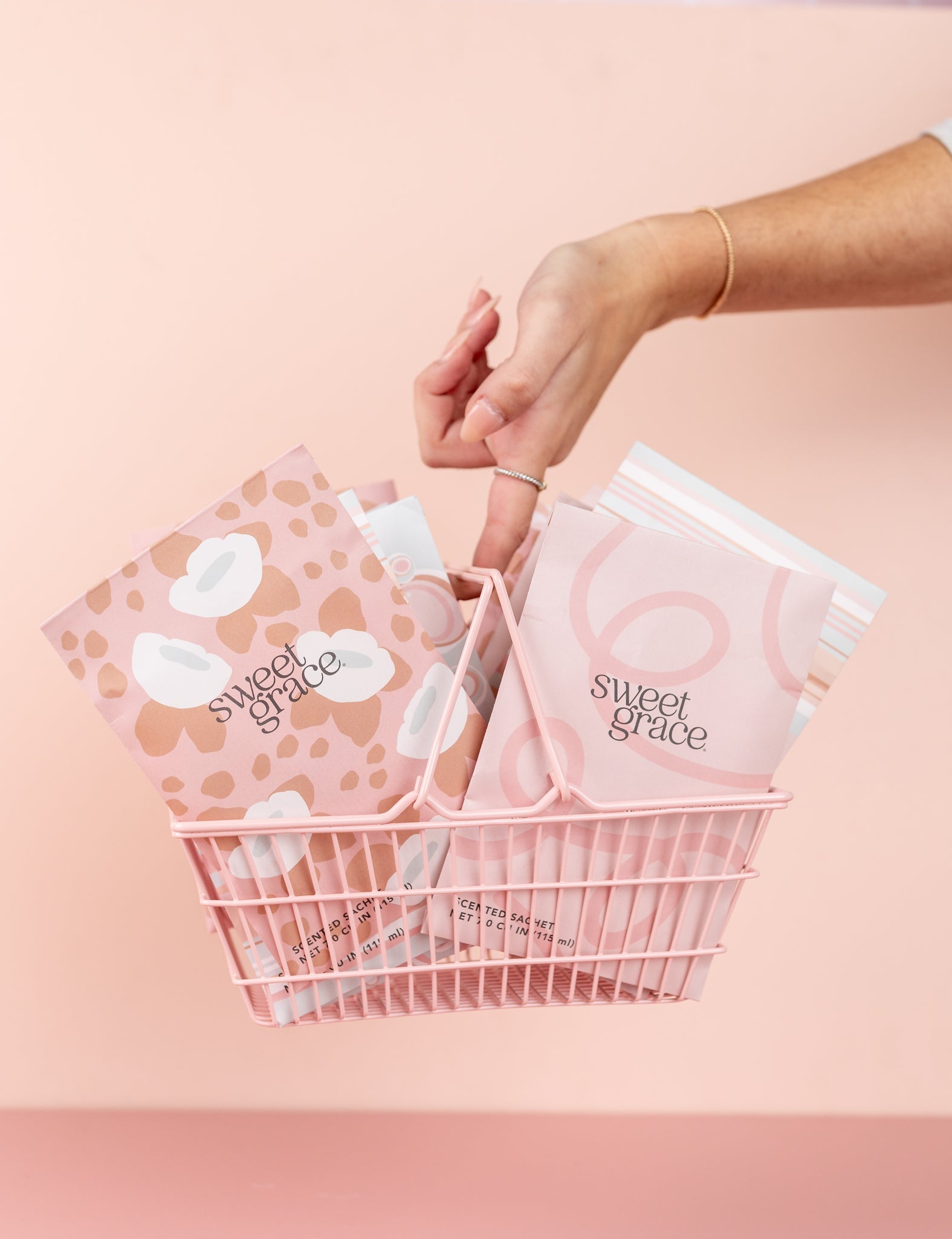 Hand holding a pink wire basket of Bridgewater Sweet Grace mod swirl sachets