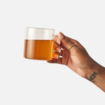 Hand holding a glass mug of brewed Big Heart Breakfast Blend black tea