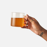 Hand holding a glass mug of brewed Big Heart Breakfast Blend black tea