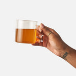 Hand holding a glass mug of brewed Cozy Night herbal tea