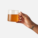Hand holding a glass mug of brewed Cozy Night herbal tea