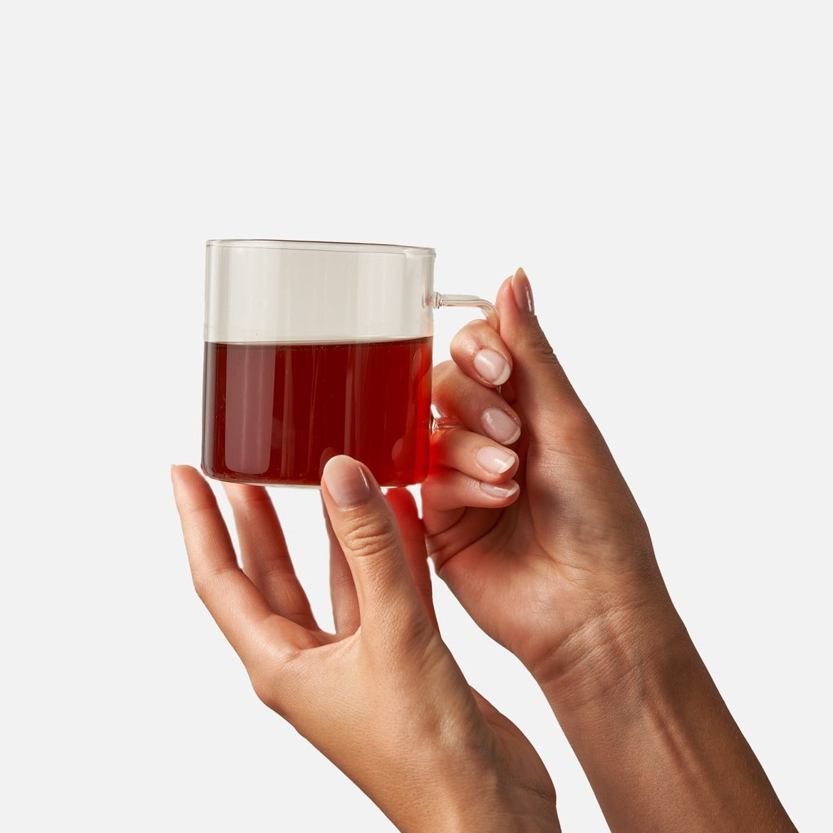 Hands holding a glass mug of brewed Winter Chai