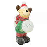 Smiling moose figure in a red knit hat and sweater holding a glowing frosted snowball