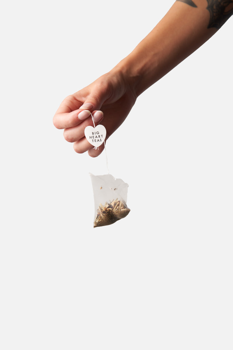 Hand dropping a Big Heart Tea compostable Calm Tummy tea bag