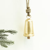 Brushed gold cowbell hanging from a knotted jute rope beside a pine branch