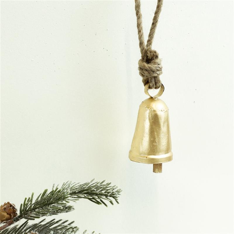Small gold cowbell on a knotted jute rope hanger against a white backdrop with pine sprigs
